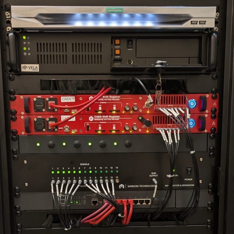 The 4-NM-2023 data acquisition cubical composed of rack-mounted computer, shift registers, aggregator and derandomiser, network switch, and uninterrupted power supply. 19-inch rack cubical containing the NM-2023 data acquisition electronics.